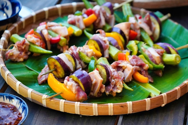 A platter of skewered vegetables and meat on a banana leaf