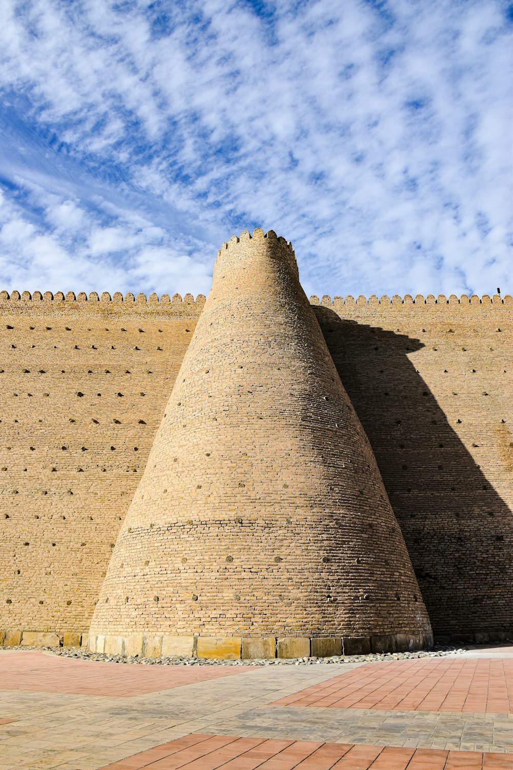 a very tall brick wall with a clock on it's side