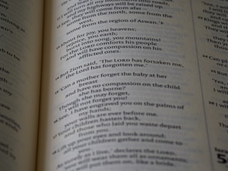 The page in the image contains text from a Bible open to a section with numbered verses. The text is printed in black ink on cream-colored paper, with varying font sizes for headings and verses.