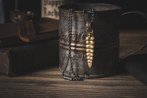 Elegant coffee cup necklace displayed on a rustic fabric background.
