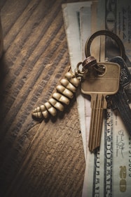 Stack of real estate contracts and keys placed neatly on a wooden table.