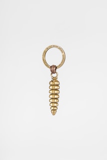 A brass keychain featuring a spiral-shaped pendant resembling a coil or screw. The pendant is attached to a round keyring engraved with the phrase 'GET BUSY LIVING OR GET BUSY DYING - COPPERISM'. The design is minimalistic and elegant.