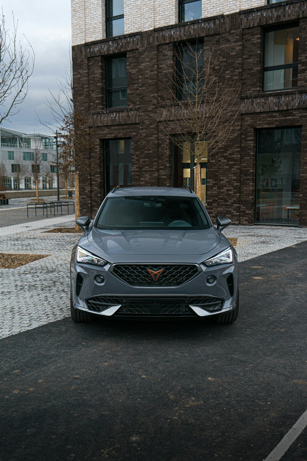 a grey car parked in front of a brick building