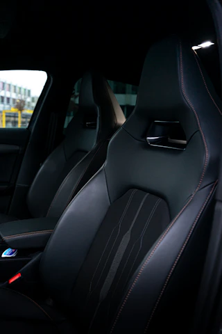 A close-up shot of a matte black luxury car interior featuring sleek chrome and gold accents under low ambient lighting.