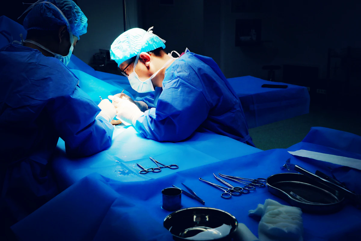 Two surgeons operating with laparoscopic instruments in a dark theatre