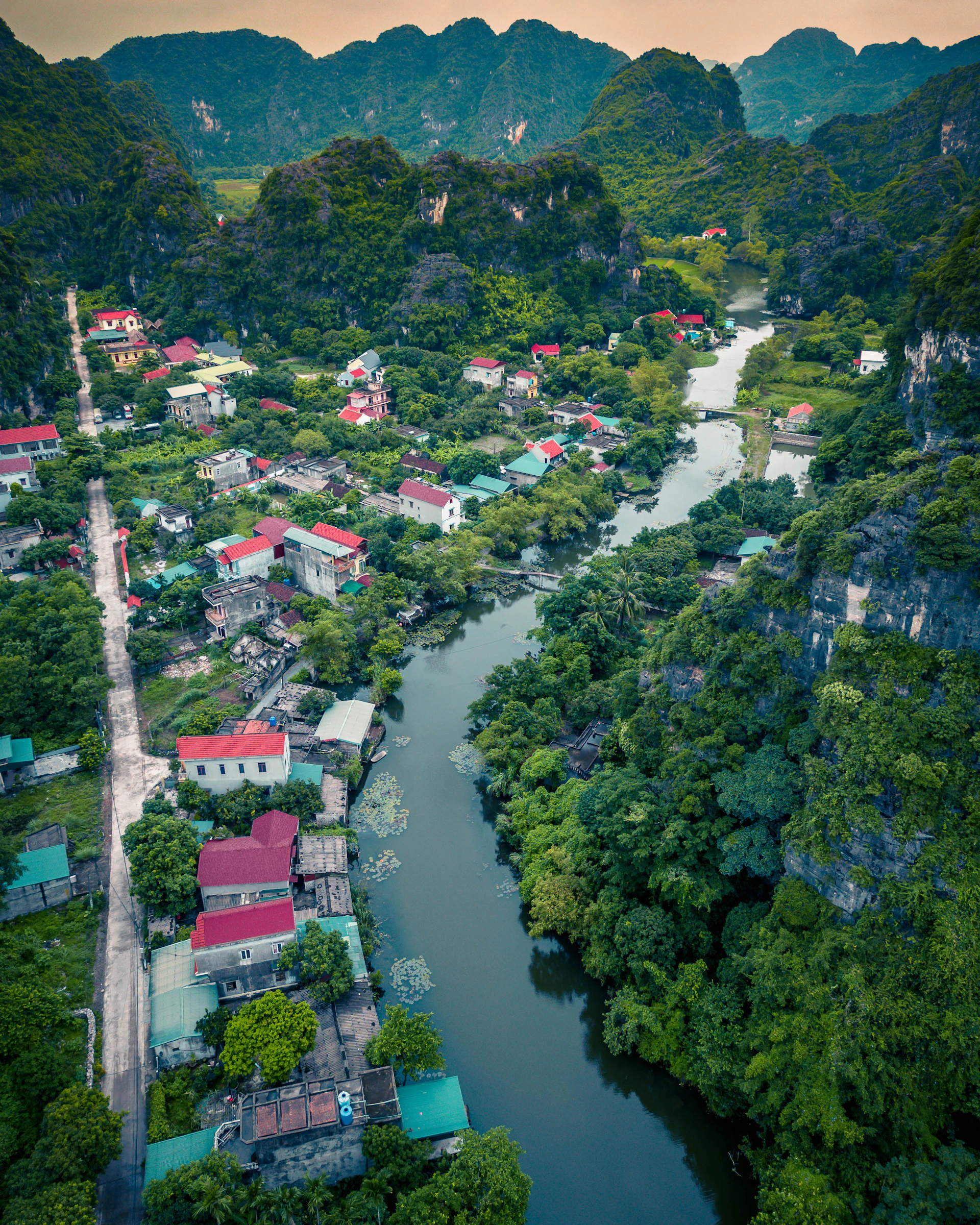 A sweeping aerial shot of a remote mountain village at sunrise, highlighting vibrant colors and intricate human activities below.
