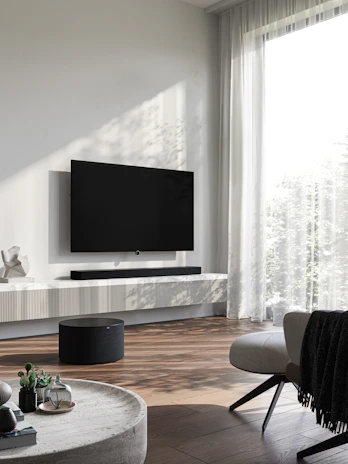 Modern living room with a sleek Crestron smart home control panel installed near the entrance.