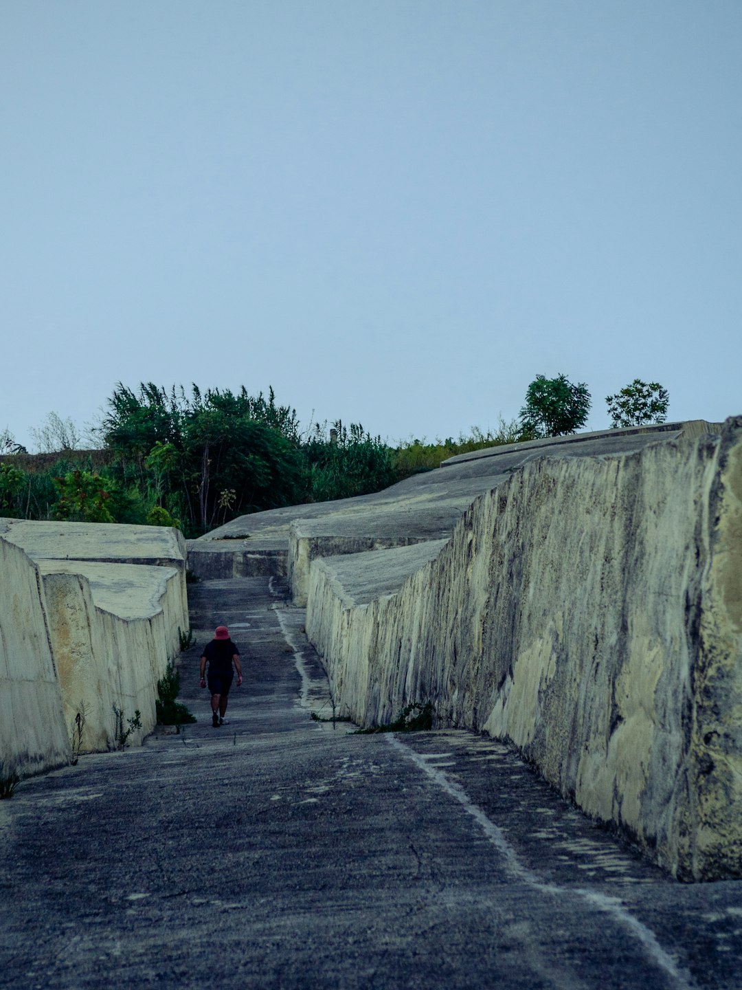 a person walking down a road next to a stone wall