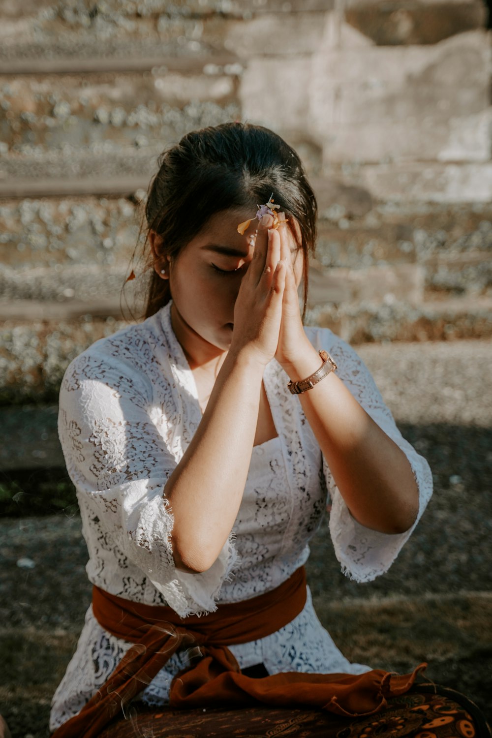 a woman sitting on the ground holding her hands to her face