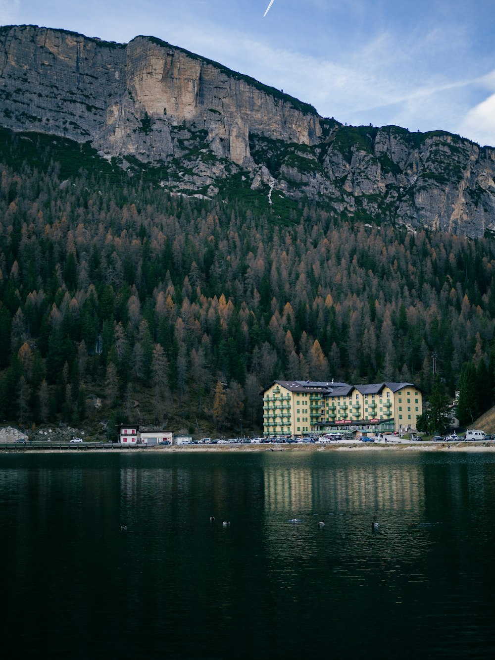a large building sitting on top of a lake next to a mountain