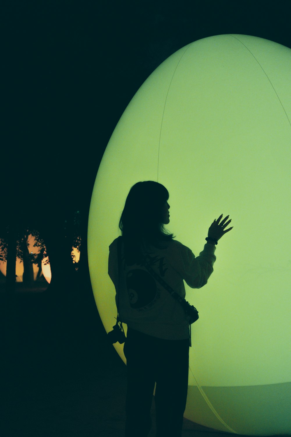 a woman standing in front of a large green ball