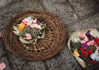 two baskets of flowers on the ground next to each other