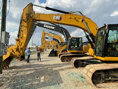 a couple of men standing next to a yellow bulldozer