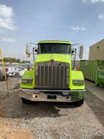 a bright green semi truck parked in a gravel lot