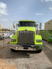 a bright green semi truck parked in a gravel lot
