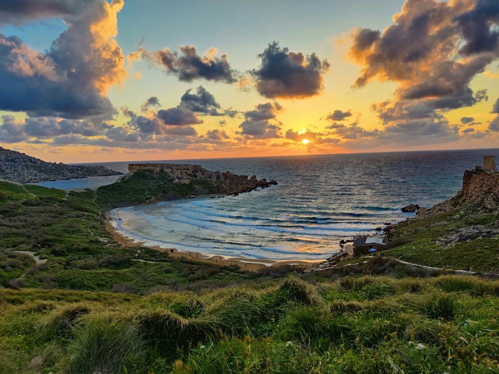 the sun is setting over the ocean on a cloudy day