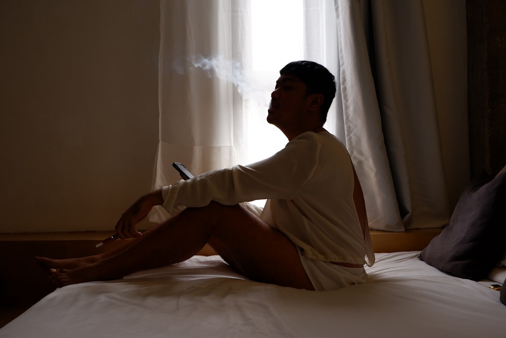 a man sitting on a bed smoking a cigarette