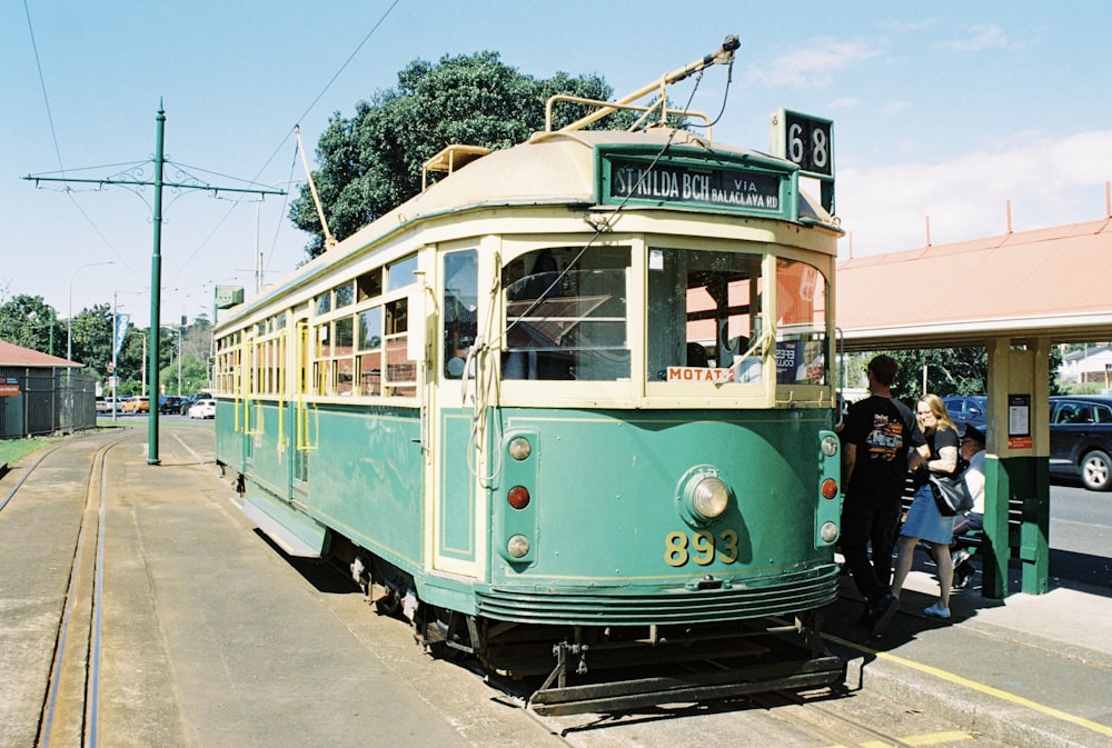 a green trolley car is parked on the side of the road