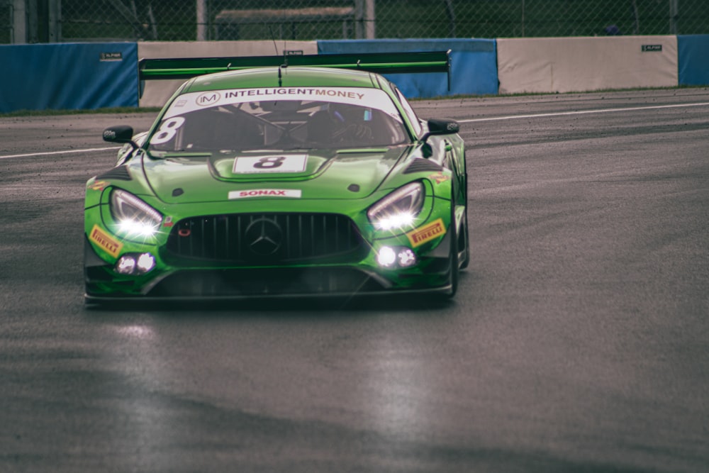 a green sports car driving on a race track