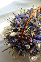 A lush arrangement of wildflowers and greenery spilling naturally from a handcrafted basket.