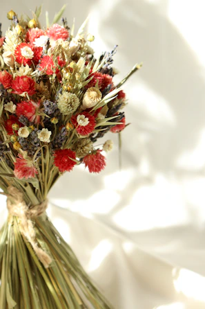 A bouquet of mixed dahlias featuring deep purples and soft whites, tied with natural twine.