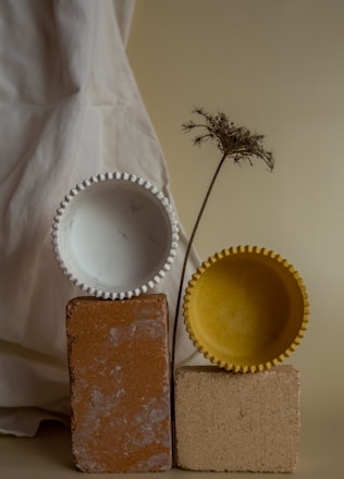 a yellow vase sitting next to a yellow and white bowl