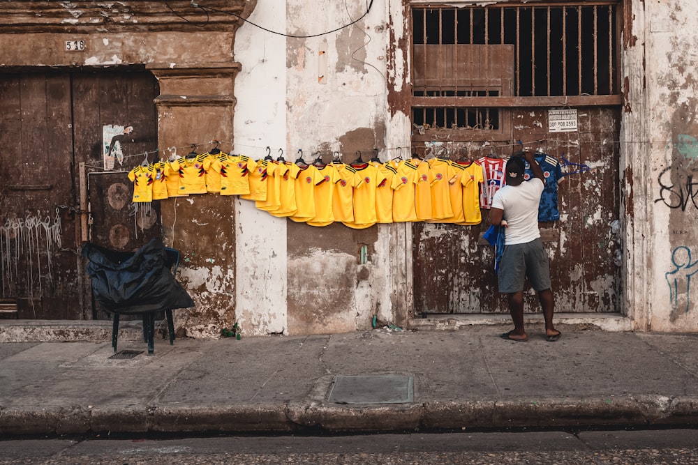 a man standing in front of a wall with bananas hanging from it