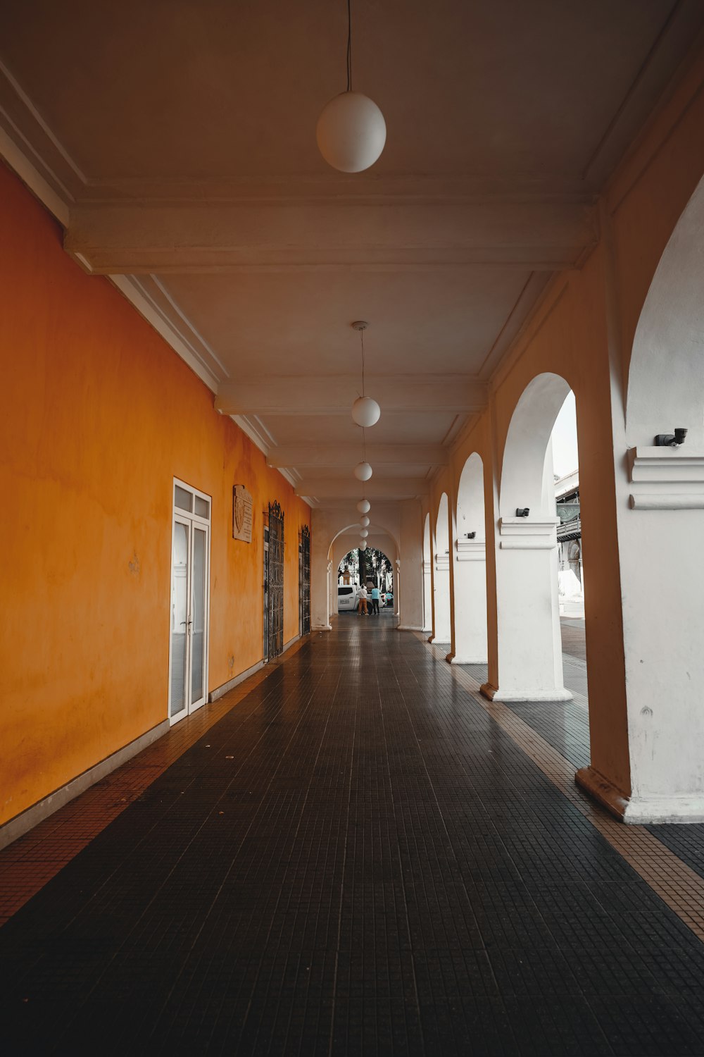 a long hallway with orange walls and white arches