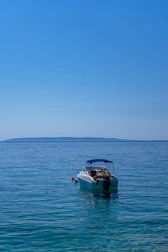 A small motorboat gliding over clear blue waters on a bright day.