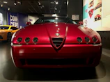 A shiny red sports car gleaming under showroom lights.