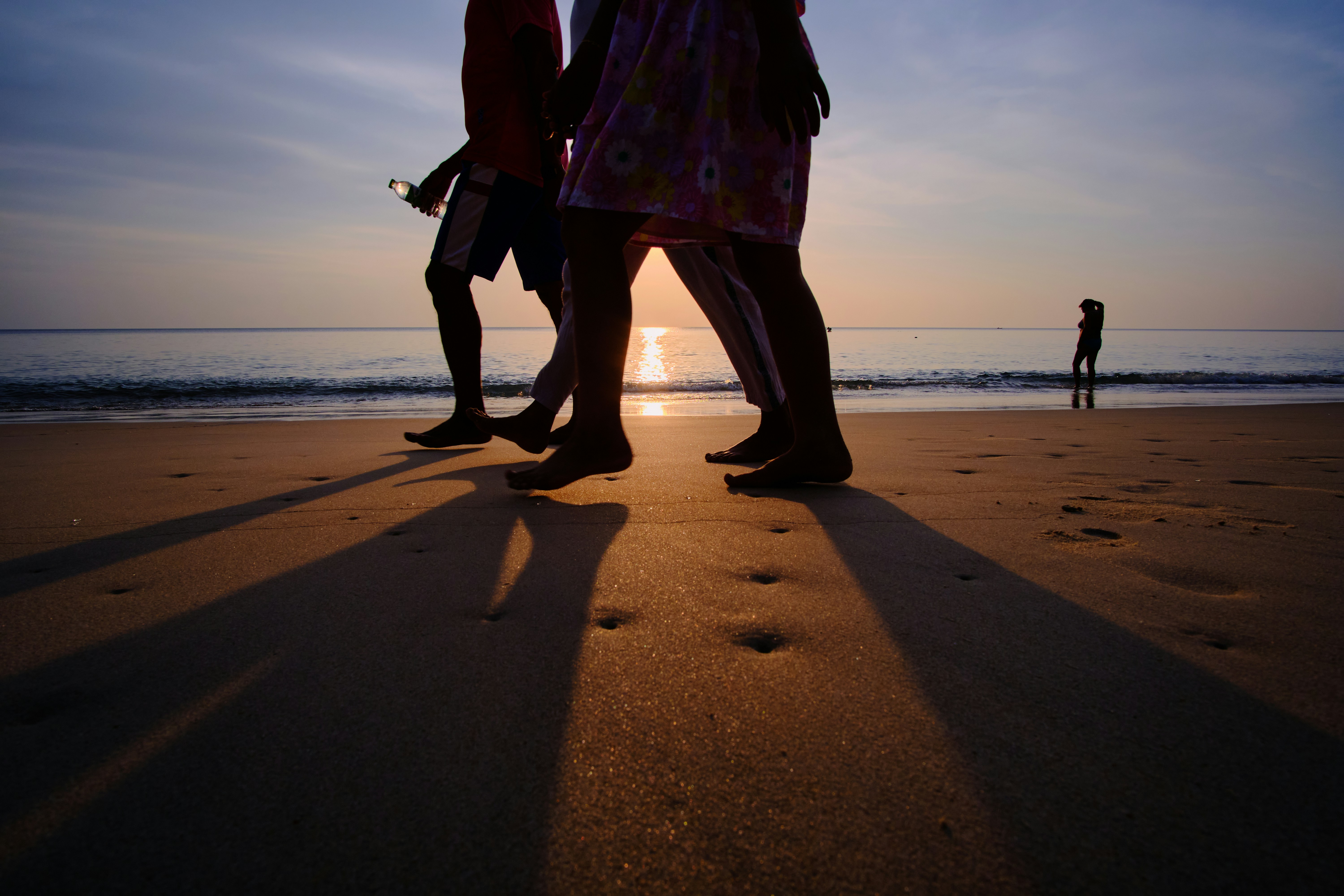 Long sandy Tra Co beach in summer, gentle waves, blue-gray sea, Vietnamese travelers walking barefoot at sunrise, airy sky, cinematic coastal scene, ultra detailed