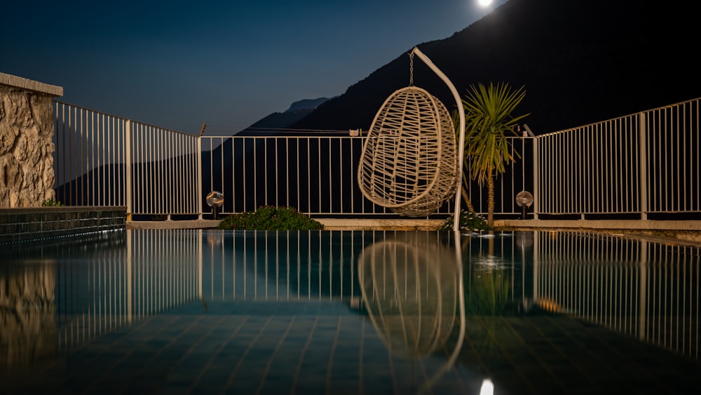 a pool at night with a hanging chair next to it