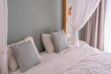 Close-up of a neatly made double bed with soft linens and decorative pillows