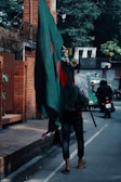 a person walking down a street holding a green flag