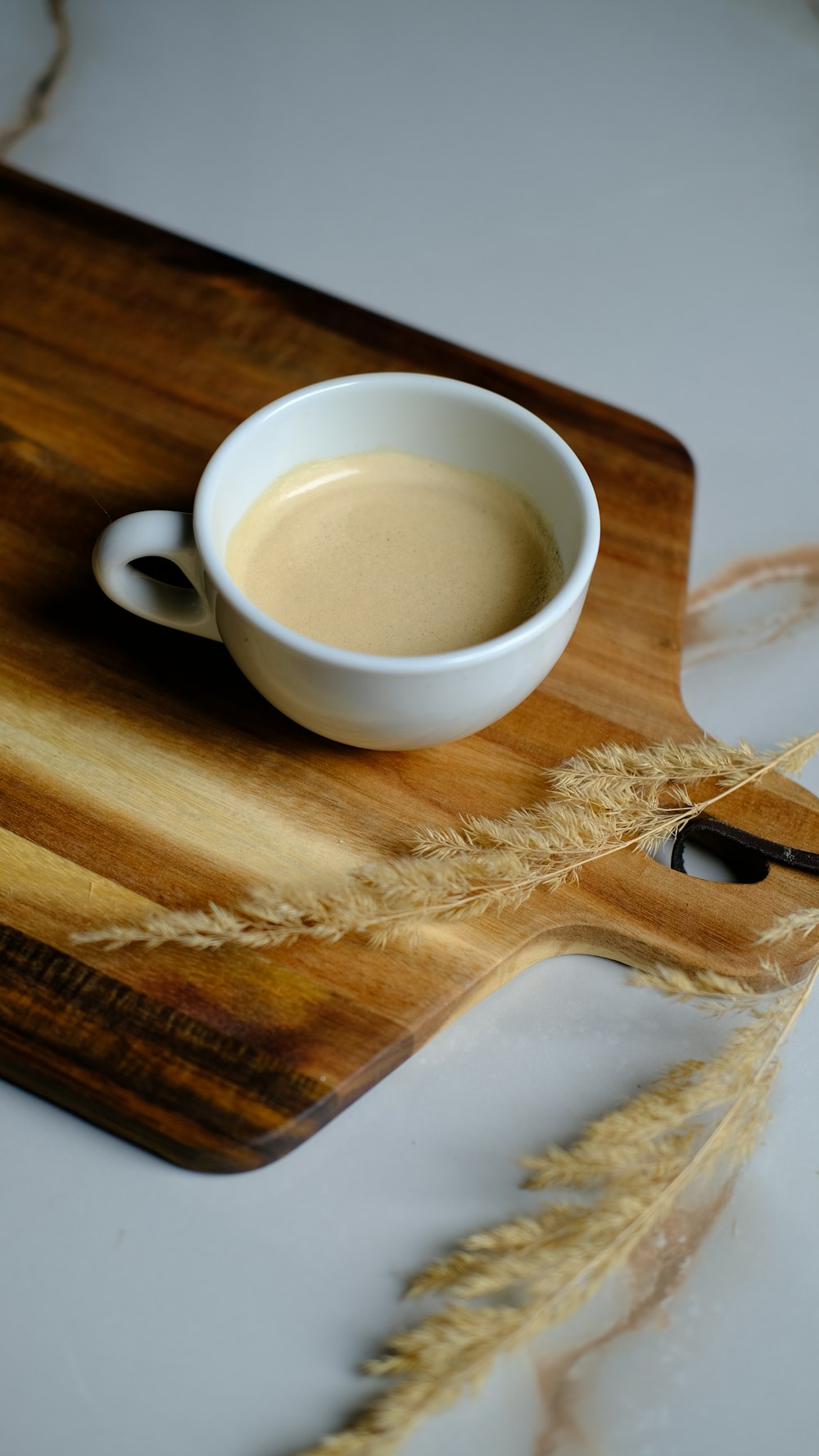 una tazza di caffè seduta sopra un tagliere di legno