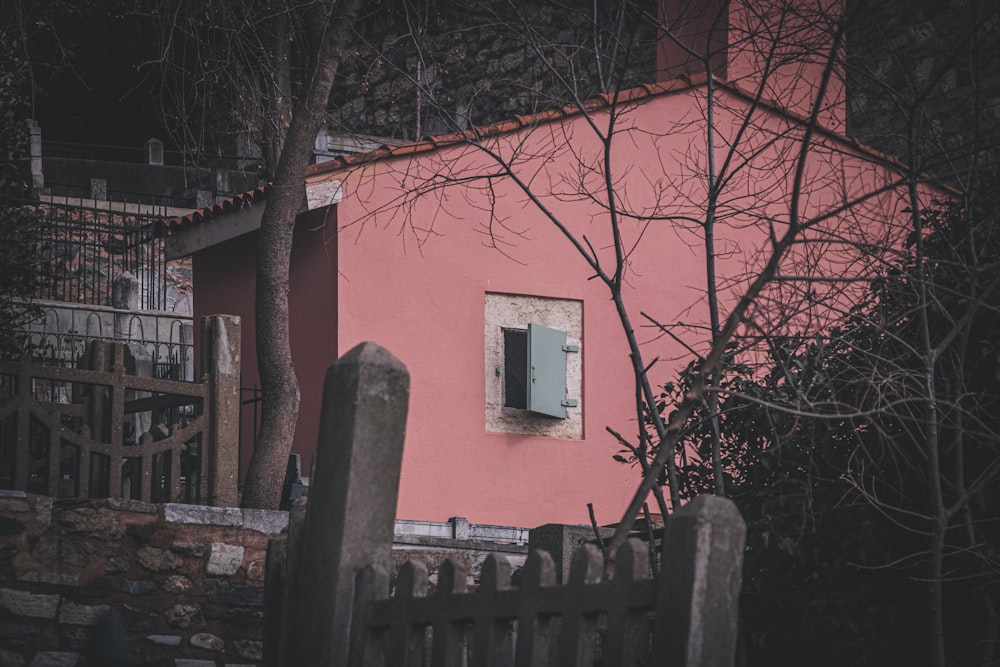 a pink house with a window and a fence