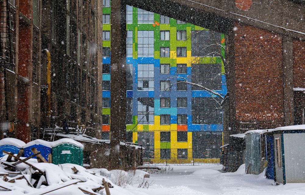 a snowy day in a city with a colorful building in the background