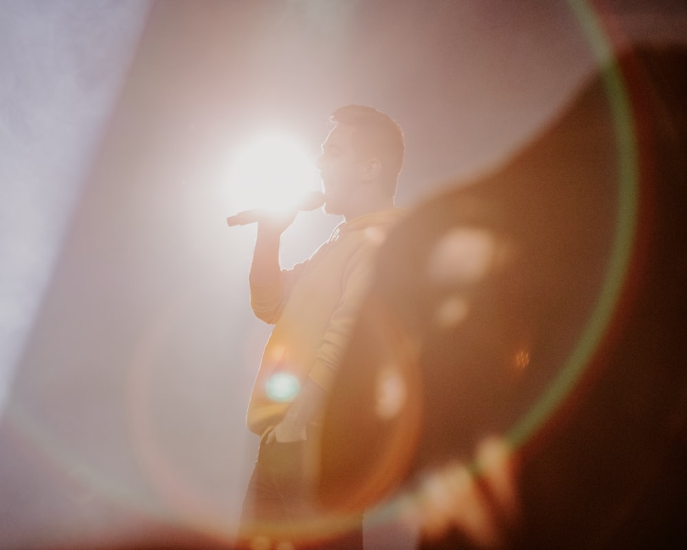 a man standing in front of a spotlight holding a microphone