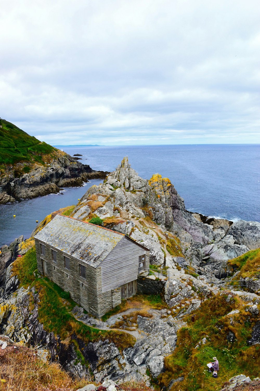 an old shack sitting on top of a rocky hill next to the ocean