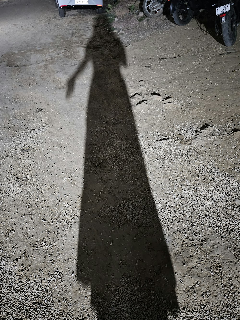 a shadow of a person standing in the middle of a road