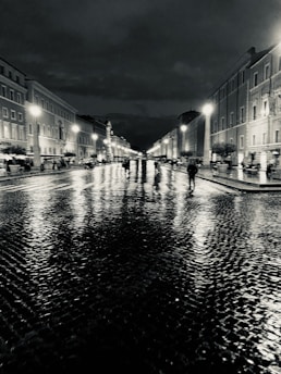 Urban nighttime street with wet cobblestones reflecting neon lights.