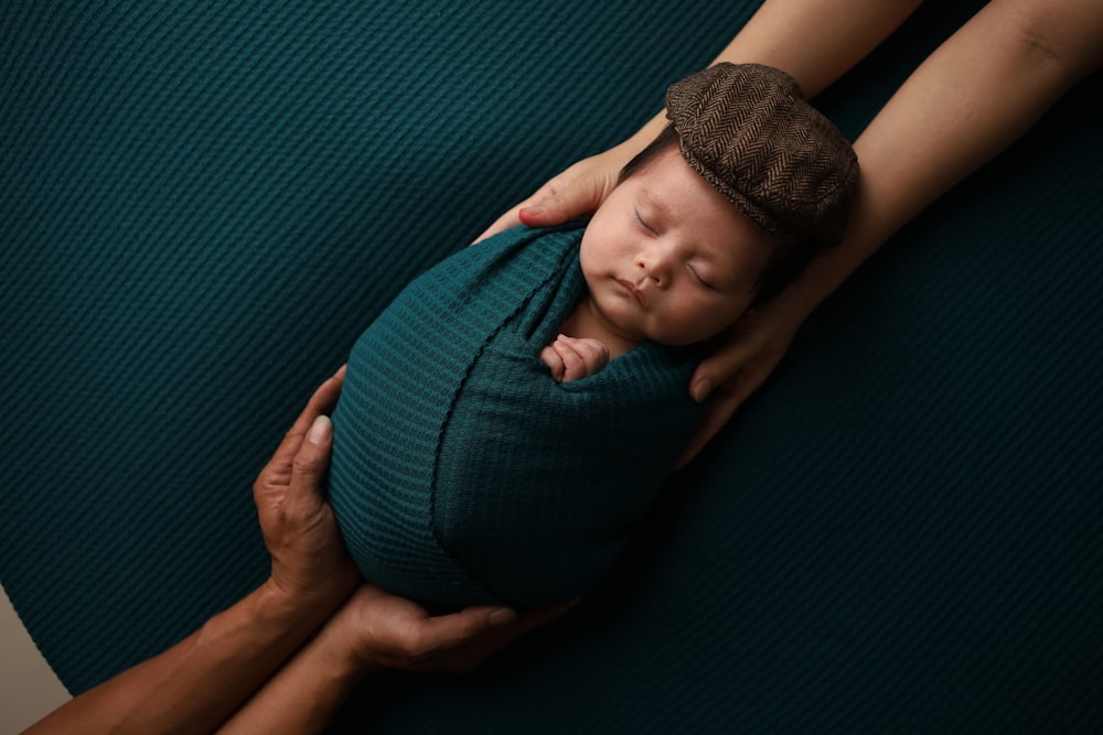 Ein Neugeborenes, eingewickelt in eine Decke, das von einem Mann gehalten wird