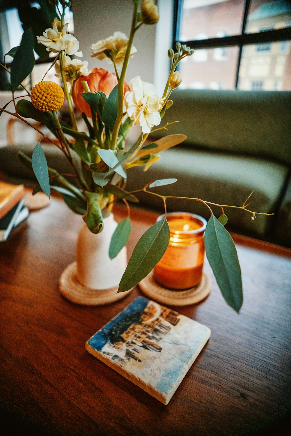 eine Vase mit Blumen und einer Kerze auf einem Tisch