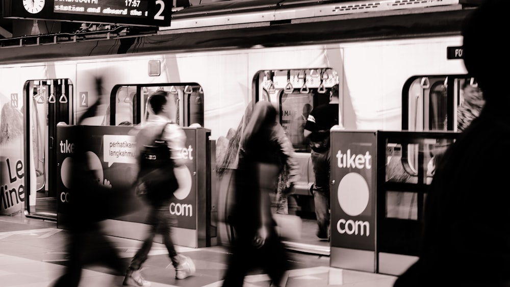 une photo en noir et blanc de personnes marchant près d’un train