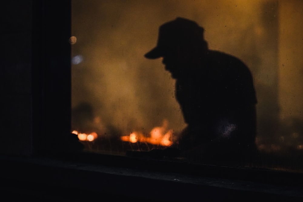 a man standing in front of a fire with a hat on