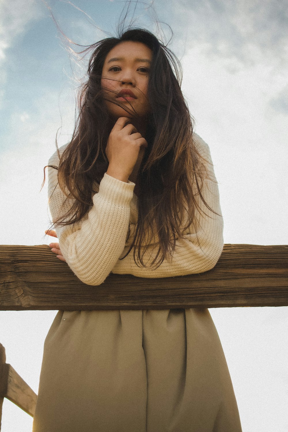 a woman leaning on a fence with her hands on her chin