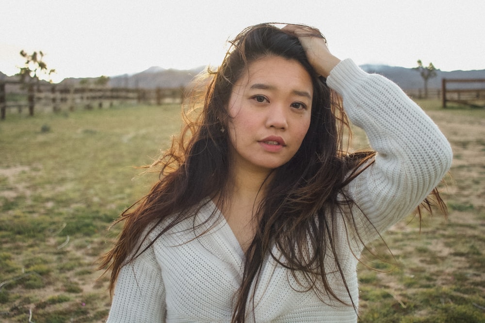 a woman with long hair standing in a field