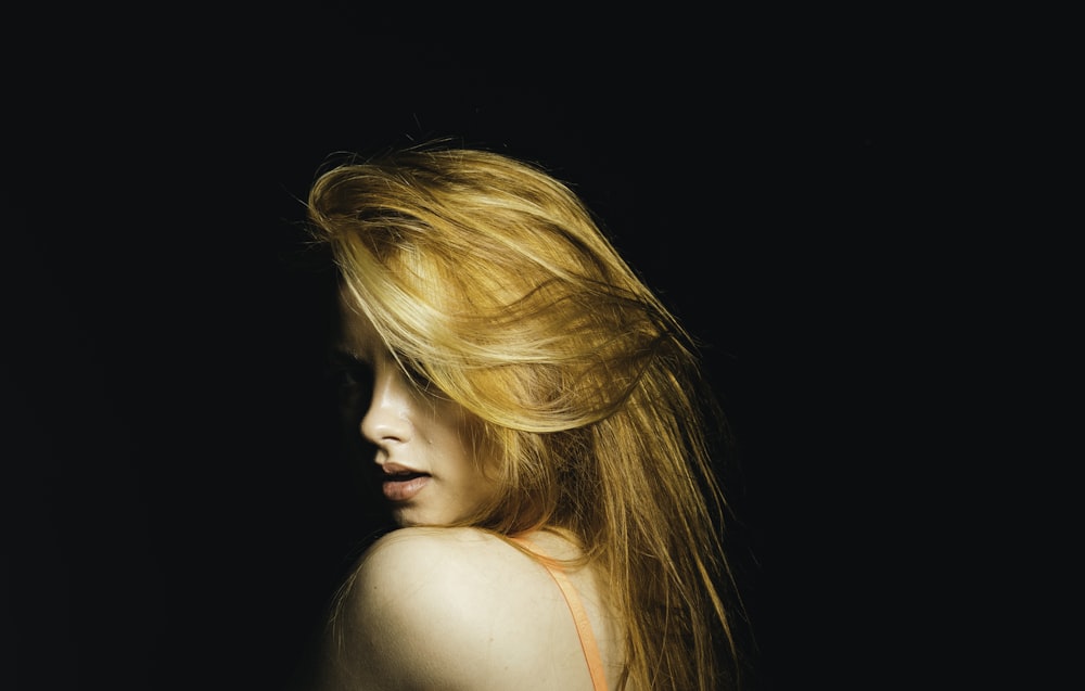 a woman with long blonde hair standing in the dark