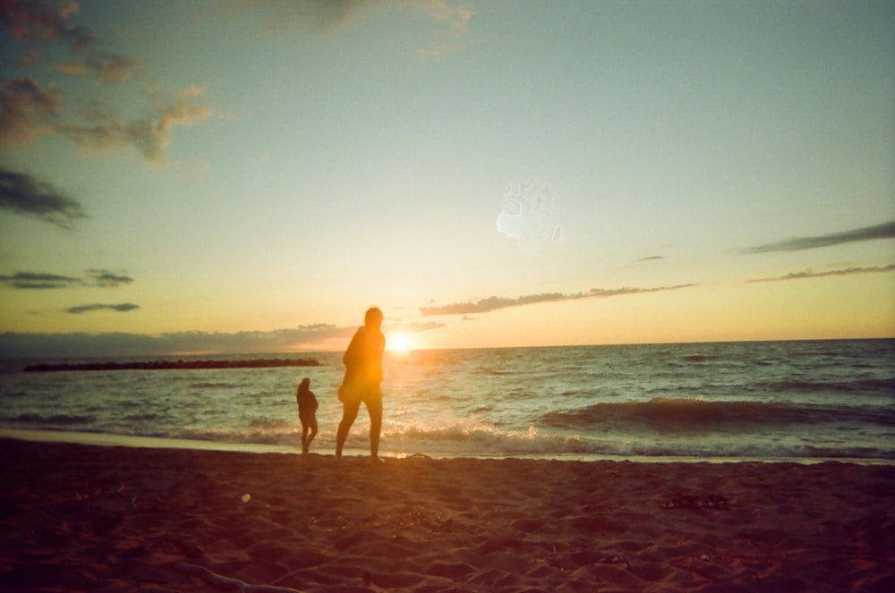 Una persona y un niño en una playa al atardecer