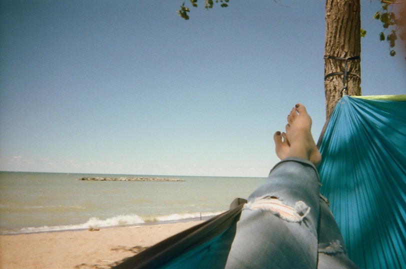 a person laying in a hammock on the beach